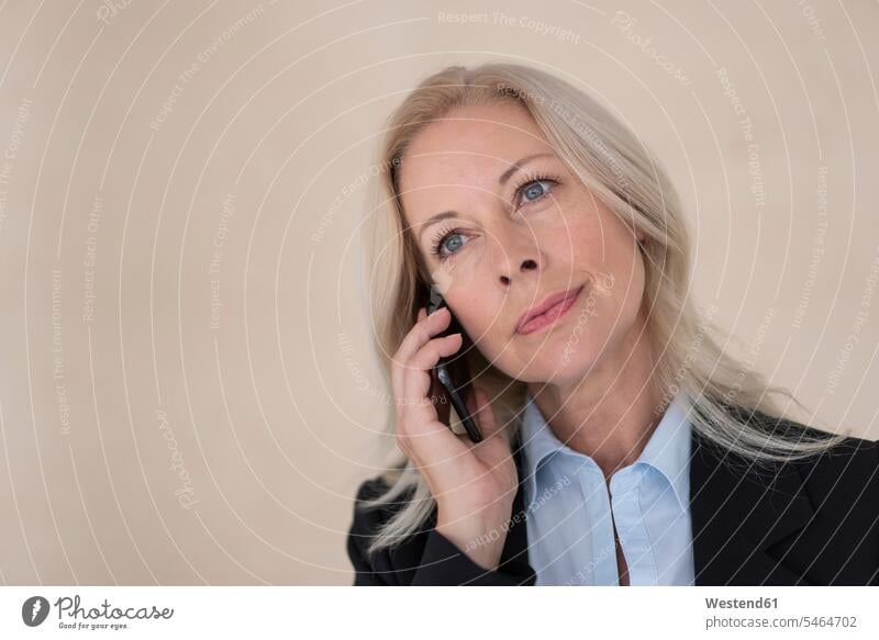 Nahaufnahme einer Unternehmerin, die mit ihrem Handy im Büro gegen die Wand telefoniert Farbaufnahme Farbe Farbfoto Farbphoto Deutschland Innenaufnahme