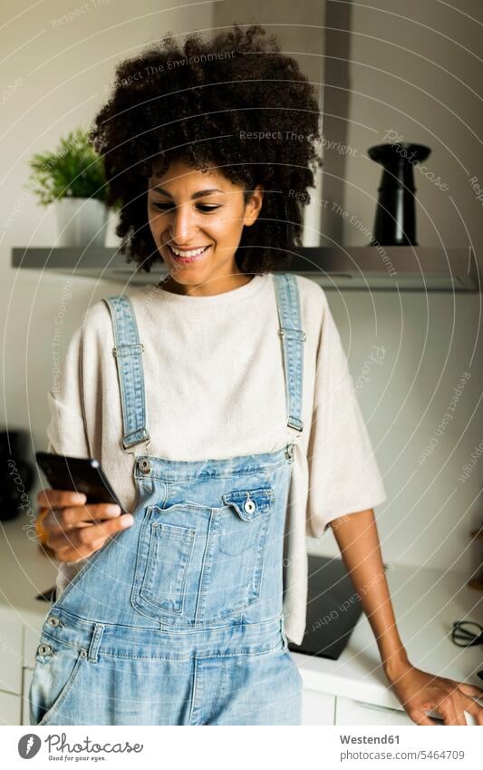 Lächelnde Frau mit Handy in der Küche zu Hause Mobiltelefon Handies Handys Mobiltelefone lächeln weiblich Frauen Zuhause daheim Telefon telefonieren