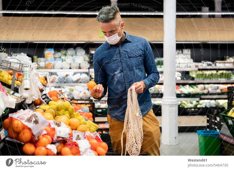 Mann mit Gesichtsmaske kauft Obst im Supermarkt Farbaufnahme Farbe Farbfoto Farbphoto Spanien Freizeitkleidung Freizeitbekleidung casual Innenaufnahme