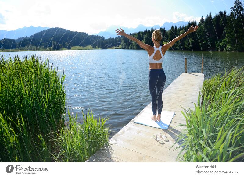 Deutschland, Mittenwald, Rückenansicht einer Frau, die auf einem Steg am See Yoga praktiziert Bootssteg Anleger Stege Landesteg Anlegestellen Landestege