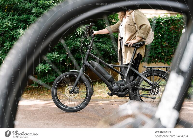 Frau mit Elektrofahrrad durchs Rad gesehen Farbaufnahme Farbe Farbfoto Farbphoto Spanien E-Bike Elektrorad eBike eBikes E-Bikes Fahrrad Fahrräder Räder