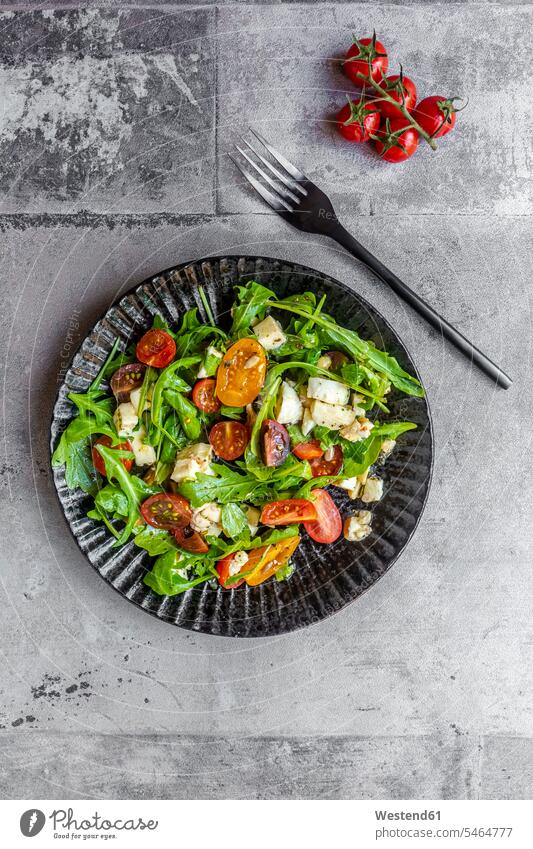 Teller mit vegetarischem Salat mit Rucola, Tomaten, Nüssen und Mozzarella-Käse Draufsicht von oben Aufsicht Vogelperspektive Nahaufnahme close up close-up