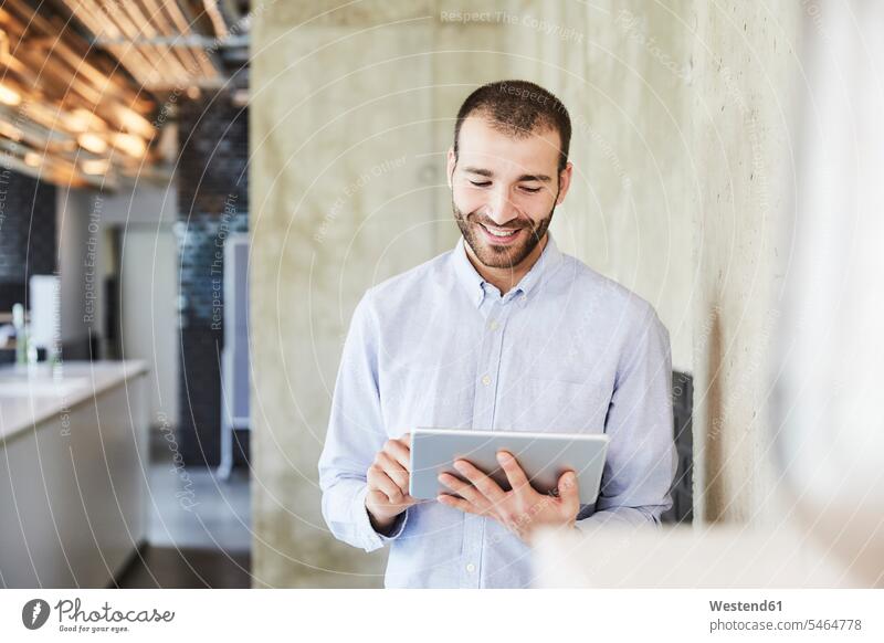 Lächelnder Geschäftsmann mit Tablet in einem modernen Büro Office Büros Businessmann Businessmänner Geschäftsmänner lächeln Tablet Computer Tablet-PC Tablet PC