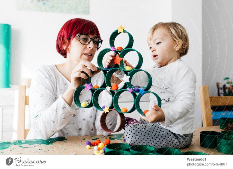 Mutter und Tochter basteln zu Hause mit Zubehör für den Bau eines Weihnachtsbaums Leute Menschen People Person Personen Europäisch Kaukasier kaukasisch