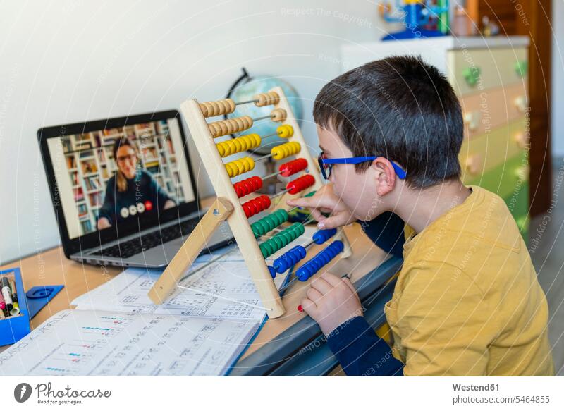 Junge mit Abakus am Schreibtisch, während der Lehrer während eines Videoanrufs im Rahmen des Pandemie-Heimunterrichts Farbaufnahme Farbe Farbfoto Farbphoto