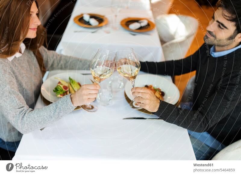Lächelndes Paar stößt in einem Restaurant mit Weingläsern an Weinglas lächeln anstoßen zuprosten anstossen Pärchen Paare Partnerschaft Lokal Speiserestaurant