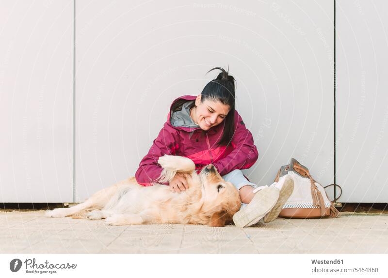 Glückliche junge Frau streichelt und spielt mit ihrem Golden Retriever Hund Hunde glücklich glücklich sein glücklichsein weiblich Frauen streicheln spielen