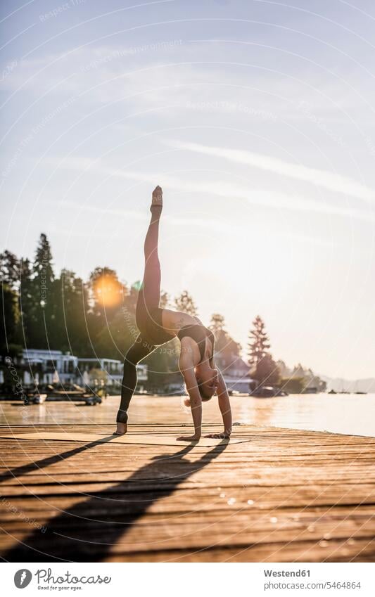 Frau praktiziert Yoga auf einem Steg an einem See Stege Anlegestelle Seen Übung Uebung Übungen Uebungen weiblich Frauen Gewässer Wasser Erwachsener erwachsen