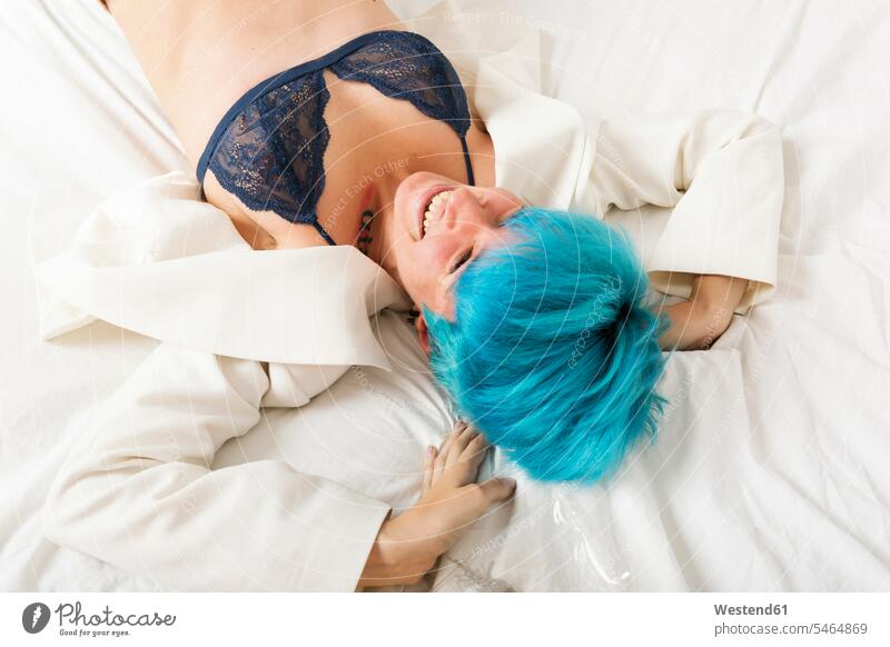 Grunge lesbische Frau auf dem Bett liegend türkis türkisfarben liegt lachen weiblich Frauen lächeln Lesbe Lesben Lesbierin Homosexuelle Frauen Lesbierinnen