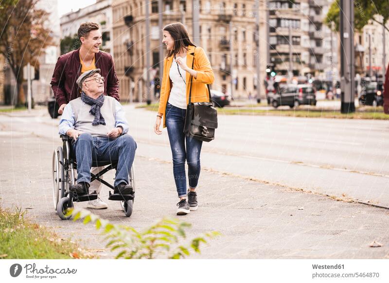 Älterer Mann im Rollstuhl verbringt Zeit mit seinen Enkelkindern Leute Menschen People Person Personen Europäisch Kaukasier kaukasisch Gruppe von Menschen