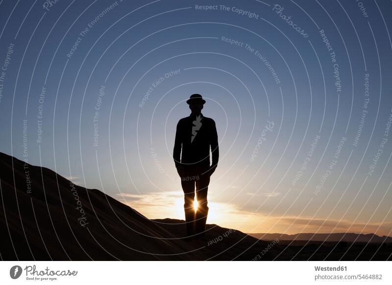 Marokko, Merzouga, Erg Chebbi, Silhouette eines Mannes mit Bowler-Hut auf einer Wüstendüne bei Sonnenuntergang Melone Bowlerhut Bowler Hat Sonnenuntergänge