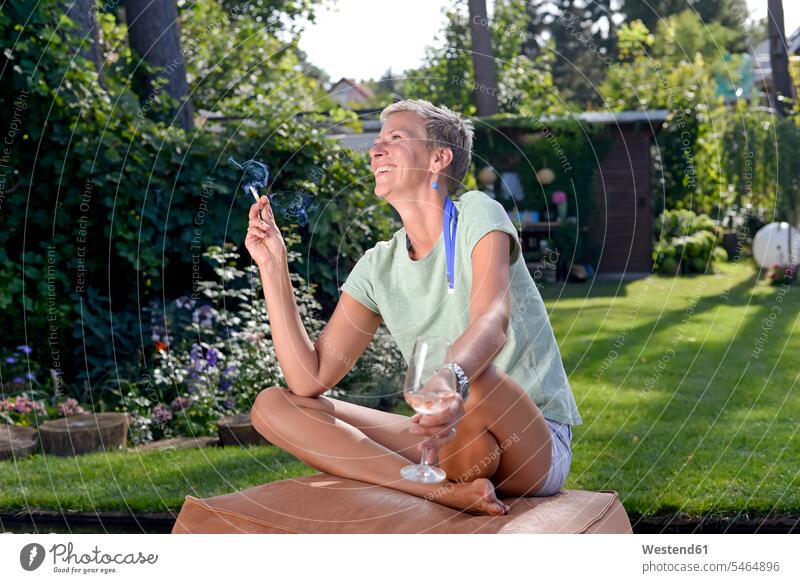 Lachende Frau beim Rauchen im Garten im Sommer Gärten Gaerten weiblich Frauen Sommerzeit sommerlich lachen rauchen Erwachsener erwachsen Mensch Menschen Leute