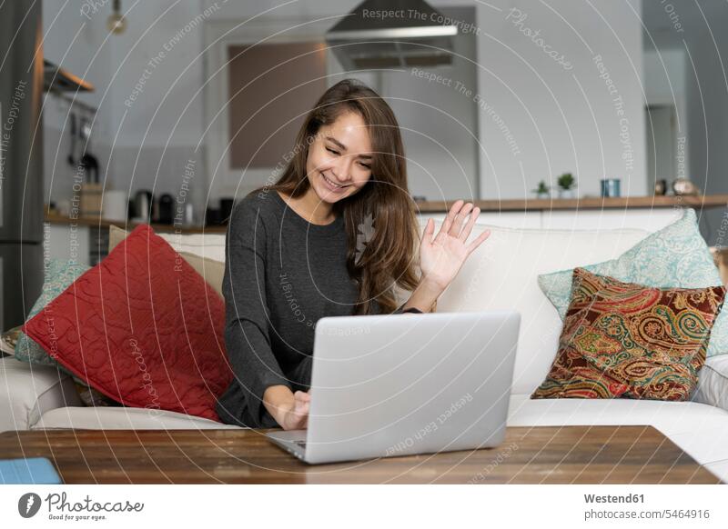 Junge Frau sitzt auf ihrer Couch und chattet auf ihrem Laptop Sofa Couches Liege Sofas Unterhaltung Gespraech Gespräch Gespraeche Gespräche Video Chat