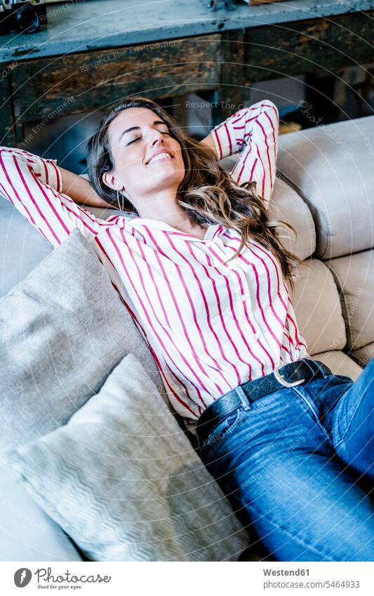 Lächelnde entspannte Frau auf Couch liegend weiblich Frauen entspanntheit relaxt Sofa Couches Liege Sofas liegt Erwachsener erwachsen Mensch Menschen Leute