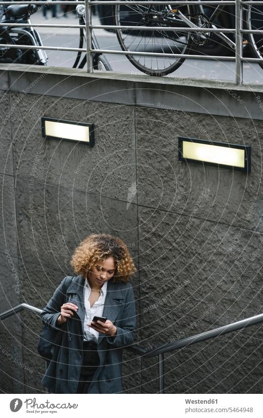 Frau mit Smartphone am Eingang einer U-Bahn-Station, Berlin, Deutschland geschäftlich Geschäftsleben Geschäftswelt Geschäftsperson Geschäftspersonen