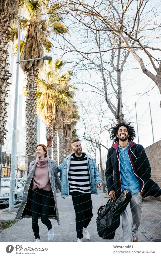 Drei glückliche Freunde beim Spaziergang in der Stadt Glück glücklich sein glücklichsein gehen gehend geht Freundschaft Kameradschaft Multikulturelle Gruppe