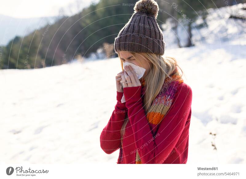 Junge blonde Frau schnäuzt sich im Winter die Nase Leute Menschen People Person Personen Europäisch Kaukasier kaukasisch erwachsen Erwachsene Frauen weiblich