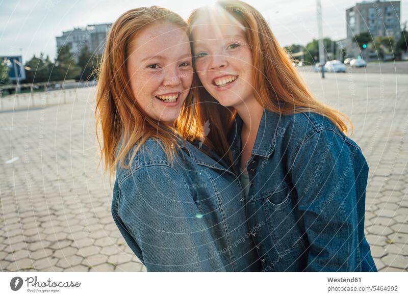 Lächelnde rothaarige Zwillinge in der Stadt, Sonnenlicht Schwester Schwestern lange Haare langes Haar langhaarig rote Haare rotes Haar rothaariger rothaariges