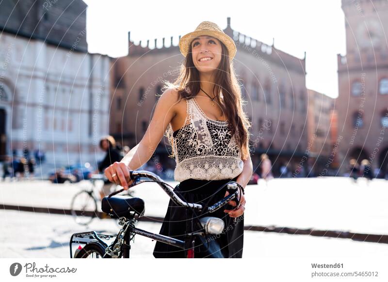 Italien, Bologna, Porträt einer modischen jungen Frau, die in der Stadt Fahrrad fährt Bikes Fahrräder Räder Rad Portrait Porträts Portraits lächeln weiblich