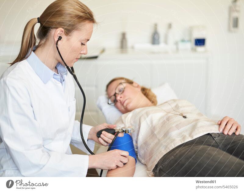 Ärztin beim Blutdruckmessen eines Patienten in einer Arztpraxis Brille Brillen Beruf Berufstätigkeit Berufe Beschäftigung Jobs Kontrolle kontrollieren