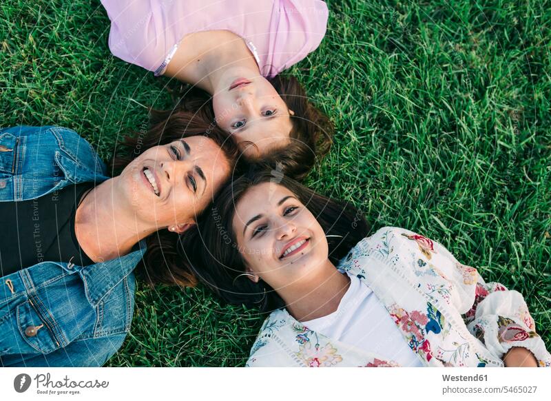 Lächelnde Mutter mit Töchtern, die auf Grasland im Park liegen Farbaufnahme Farbe Farbfoto Farbphoto Portugal Freizeitbeschäftigung Muße Zeit Zeit haben