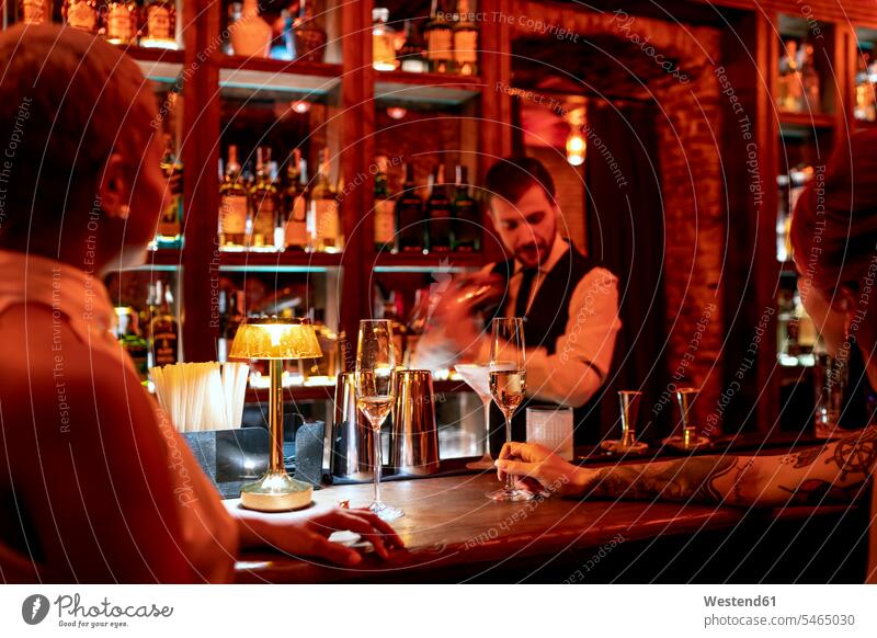 Barkeeper mixt einen Cocktail, während er an der Bartheke im Pub steht Farbaufnahme Farbe Farbfoto Farbphoto Innenaufnahme Innenaufnahmen innen drinnen