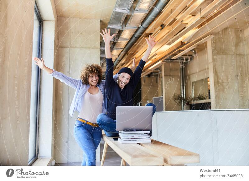 Aufgeregter Mann und Frau mit Laptop im modernen Büro Freiberufler freiberuflich freie Berufe Deutschland Pausenraum Geschäftsfrau Geschäftsfrauen Businesswomen