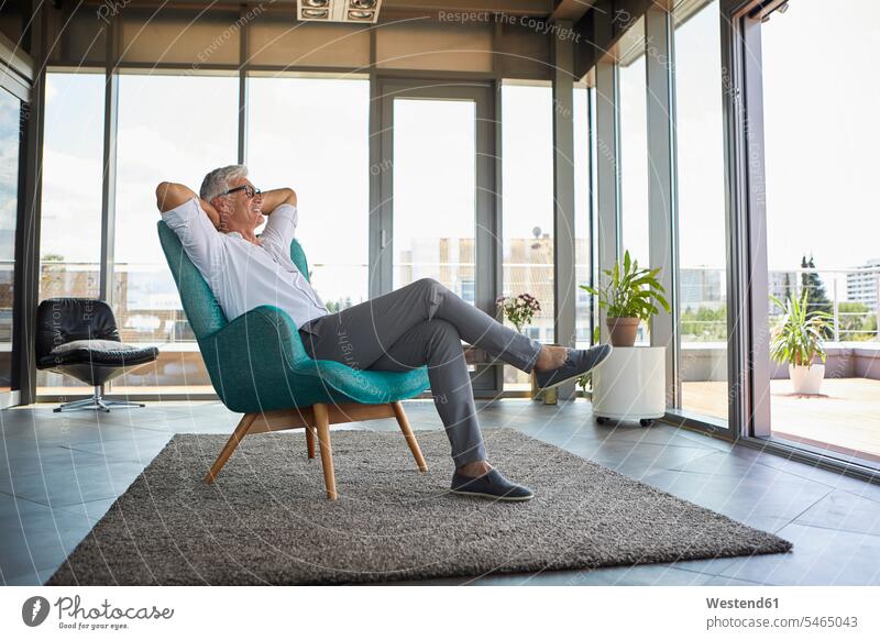 Lächelnd reifen Mann entspannt im Sessel am Fenster zu Hause Männer männlich entspanntheit relaxt Zuhause daheim lächeln Erwachsener erwachsen Mensch Menschen