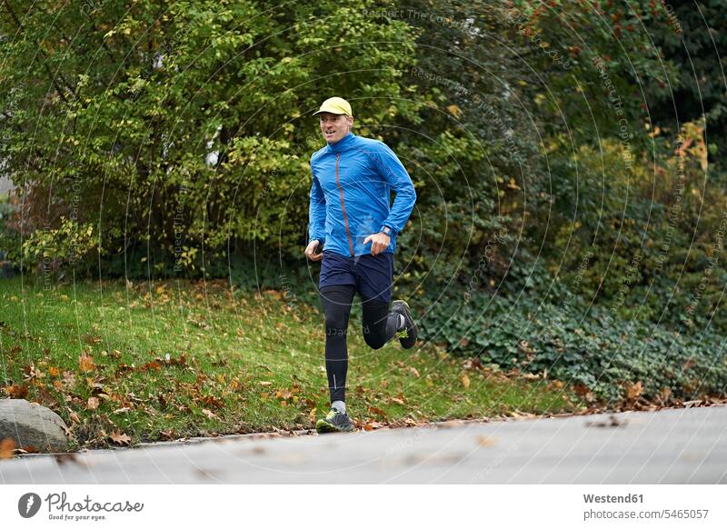 Älterer Mann in Sportkleidung läuft auf Fußweg durch Gras Farbaufnahme Farbe Farbfoto Farbphoto Außenaufnahme außen draußen im Freien Tag Tageslichtaufnahme