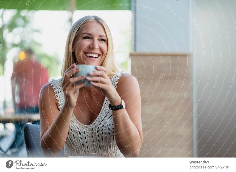 Porträt einer glücklichen blonden Frau beim Kaffeetrinken in einem Café entspannen relaxen sommerlich Sommerzeit freuen Frohsinn Fröhlichkeit Heiterkeit
