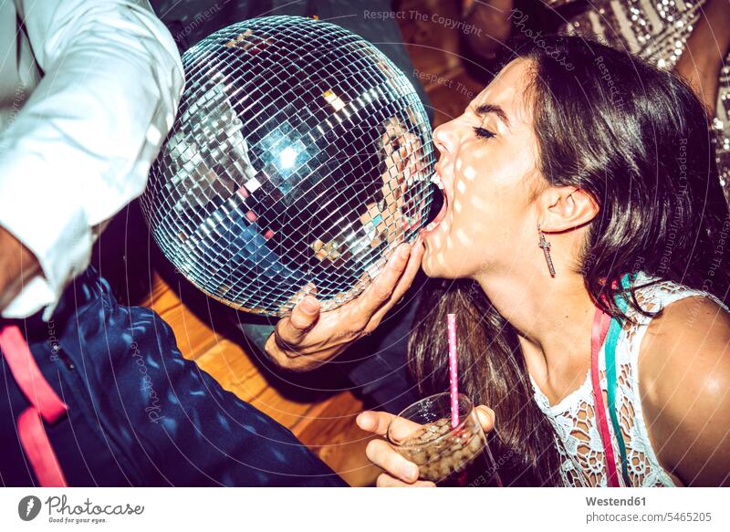 Junge Frau mit geschlossenen Augen hält Getränk und beißende Discokugel in glamouröser Party Farbaufnahme Farbe Farbfoto Farbphoto Innenaufnahme Innenaufnahmen