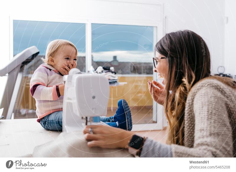 Glückliche Mutter mit kleiner Tochter zu Hause mit Nähmaschine Zuhause glücklich Gerät Eltern Familie Mensch Kind Kleinunternehmen Modedesigner Kleingewerbe