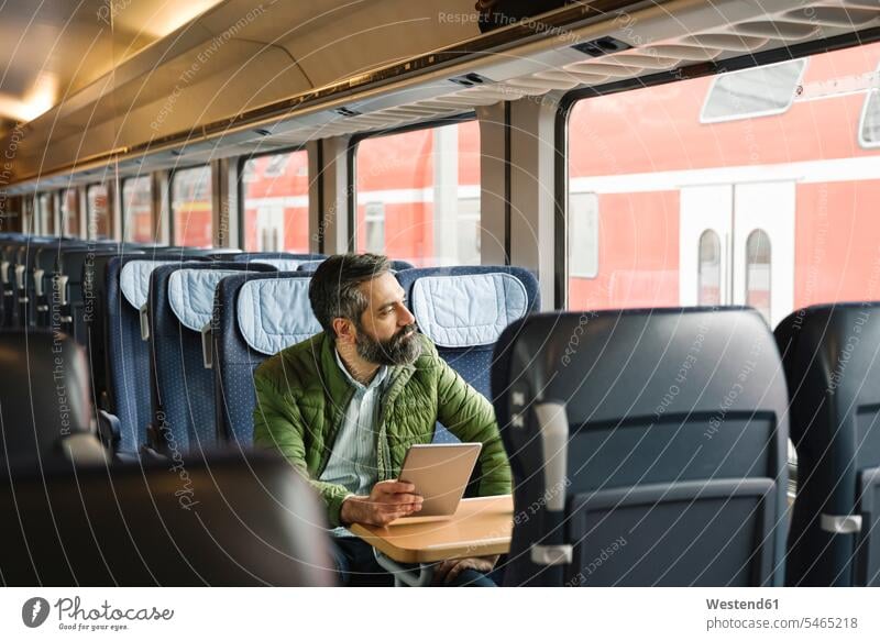 Mann sitzt im Zug und hält Tablette Job Berufe Berufstätigkeit Beschäftigung Jobs geschäftlich Geschäftsleben Geschäftswelt Geschäftsperson Geschäftspersonen