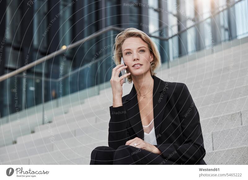 Porträt einer jungen Geschäftsfrau am Telefon auf einer Treppe sitzend im Freien Geschäftsfrauen Businesswomen Businessfrauen Businesswoman Portrait Porträts