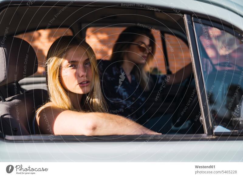 Porträt einer jungen Frau, die mit einem Freund in einem Auto sitzt Freundinnen Portrait Porträts Portraits sitzen sitzend Wagen PKWs Automobil Autos weiblich