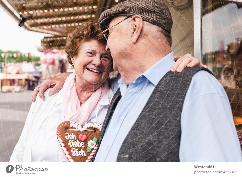 Glückliches älteres Ehepaar mit Lebkuchenherz auf Messe glücklich glücklich sein glücklichsein Seniorenpaar älteres Paar Seniorenpaare ältere Paare