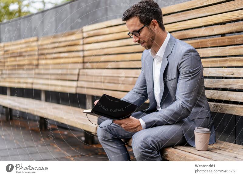 Geschäftsmann sitzt auf einer Holzbank in der Stadt und schreibt in ein Notizbuch geschäftlich Geschäftsleben Geschäftswelt Geschäftsperson Geschäftspersonen