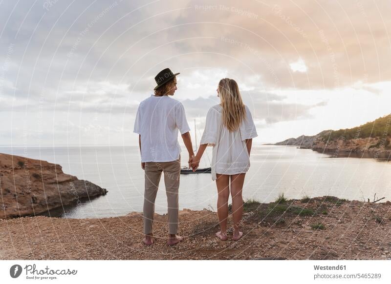 Rückansicht eines jungen verliebten Paares vor dem Meer stehend, Ibiza, Balearen, Spanien Leute Menschen People Person Personen Europäisch Kaukasier kaukasisch