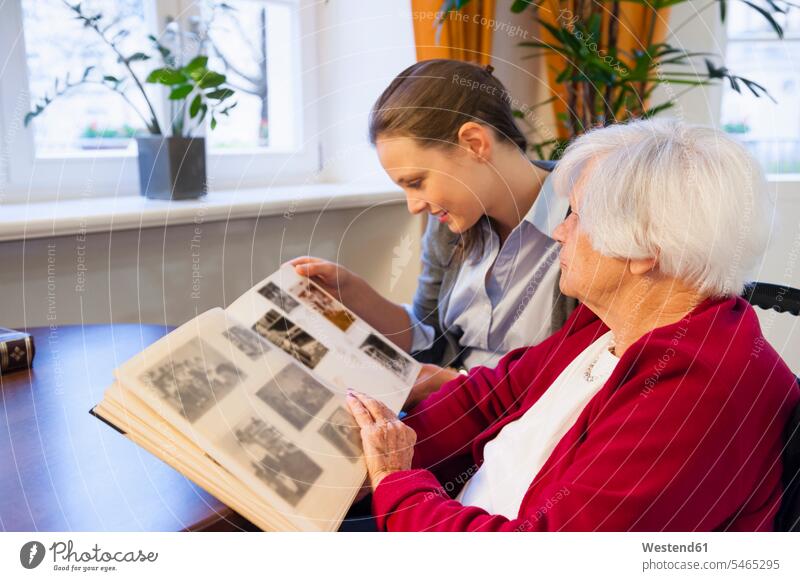 Großmutter und Enkelin schauen sich zu Hause ein Fotoalbum an Farbaufnahme Farbe Farbfoto Farbphoto Deutschland Innenaufnahme Innenaufnahmen innen drinnen