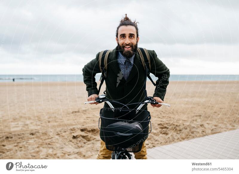 Porträt eines glücklichen Mannes mit E-Bike am Strand eBikes E-Bikes Elektrofahrrad Elektrorad Beach Straende Strände Beaches Portrait Porträts Portraits Männer