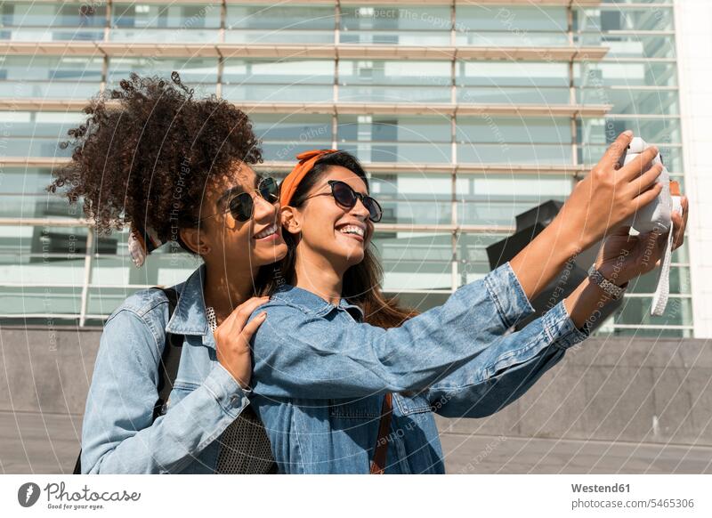 Lächelnde Freunde, die ein Selfie mit der Kamera machen, während sie auf dem Dach stehen Farbaufnahme Farbe Farbfoto Farbphoto Tag Tageslichtaufnahme