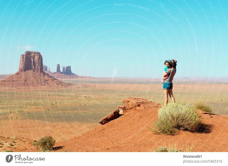 USA, Utah, Monument Valley, Mutter reist mit Baby-Mädchen, Mutter trägt Mädchen, stehend auf Aussichtspunkt Aussicht bewundern die Aussicht bewundern