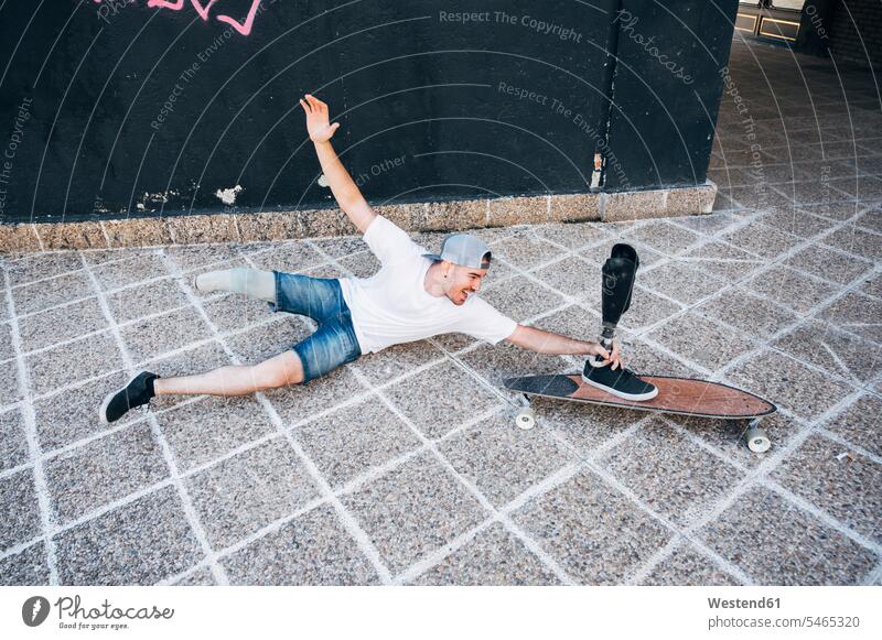 Amputierter junger Mann hat Spaß mit Beinprothese und Skateboard T-Shirts Jahreszeiten sommerlich Sommerzeit freuen Frohsinn Fröhlichkeit Heiterkeit Glück