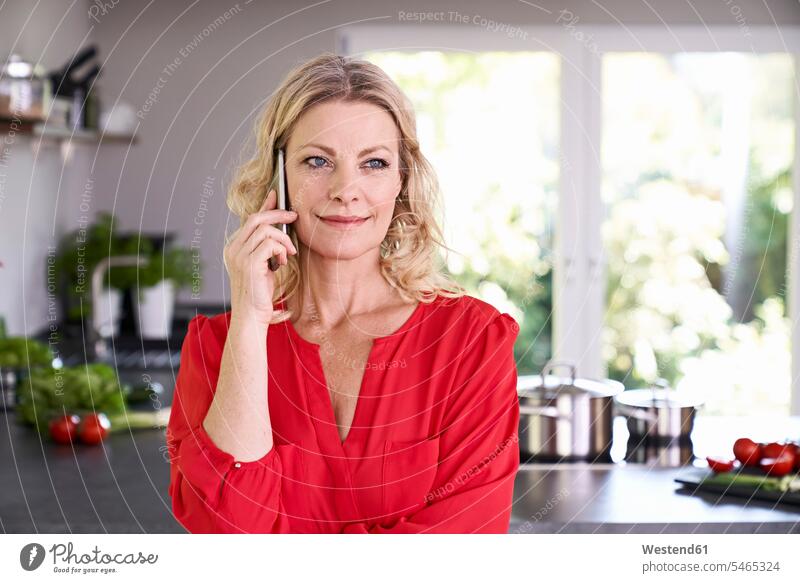 Porträt einer lächelnden Frau am Telefon in der Küche telefonieren anrufen Anruf telephonieren weiblich Frauen Portrait Porträts Portraits Küchen Handy