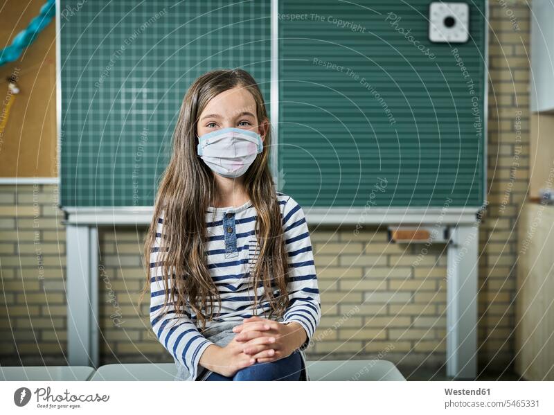 Porträt eines maskierten Mädchens im Klassenzimmer Schüler Tafel lächeln sitzen Gesundheit Schutz Sicherheit Schule Vorderansicht Innenaufnahme Portrait Tag