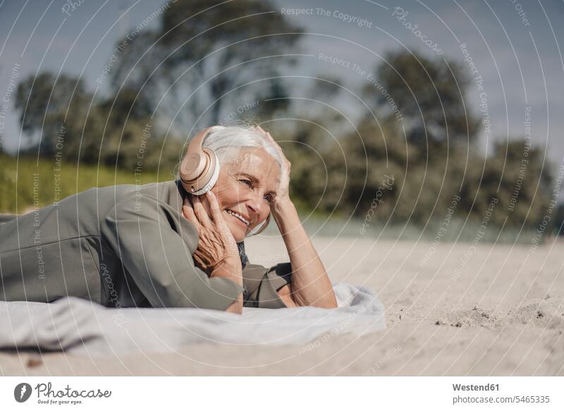 Ältere Frau hört Musik mit Kopfhörern am Strand Leute Menschen People Person Personen Europäisch Kaukasier kaukasisch 1 Ein ein Mensch eine nur eine Person