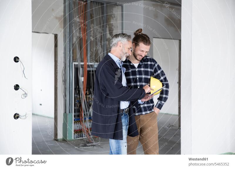 Architekt und Bauarbeiter diskutieren über digitales Tablett, während sie im renovierenden Haus stehen Farbaufnahme Farbe Farbfoto Farbphoto Deutschland