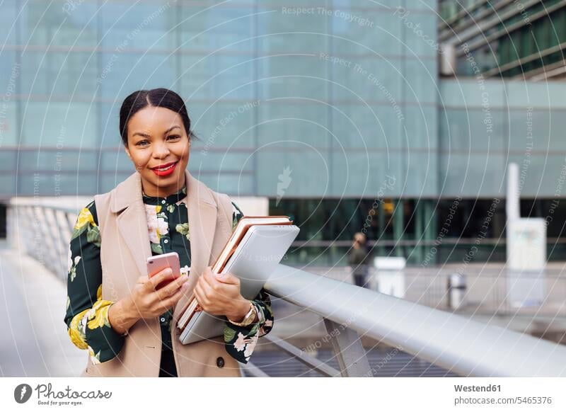 Grossbritannien, London, Porträt einer modischen Geschäftsfrau mit Handy, Laptop und Notizbuch Notebook Laptops Notebooks Portrait Porträts Portraits