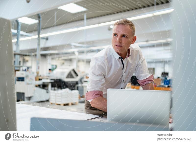 Geschäftsmann mit Laptop in einer Fabrik, der sich umsieht Job Berufe Berufstätigkeit Beschäftigung Jobs geschäftlich Geschäftsleben Geschäftswelt