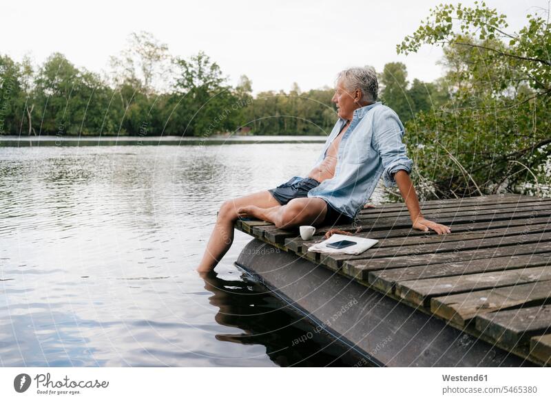 Senior Mann sitzt auf Steg an einem See Stege Anlegestelle Seen sitzen sitzend Männer männlich ältere Männer älterer Mann Senioren Gewässer Wasser Erwachsener